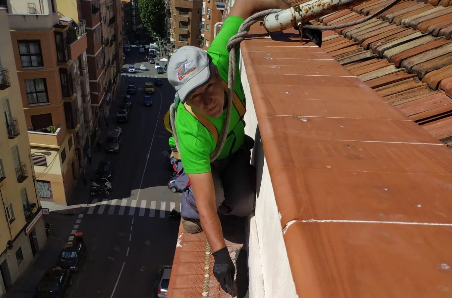 Hombre trabajando en un tejado, aplicando revestimiento en la pared exterior.